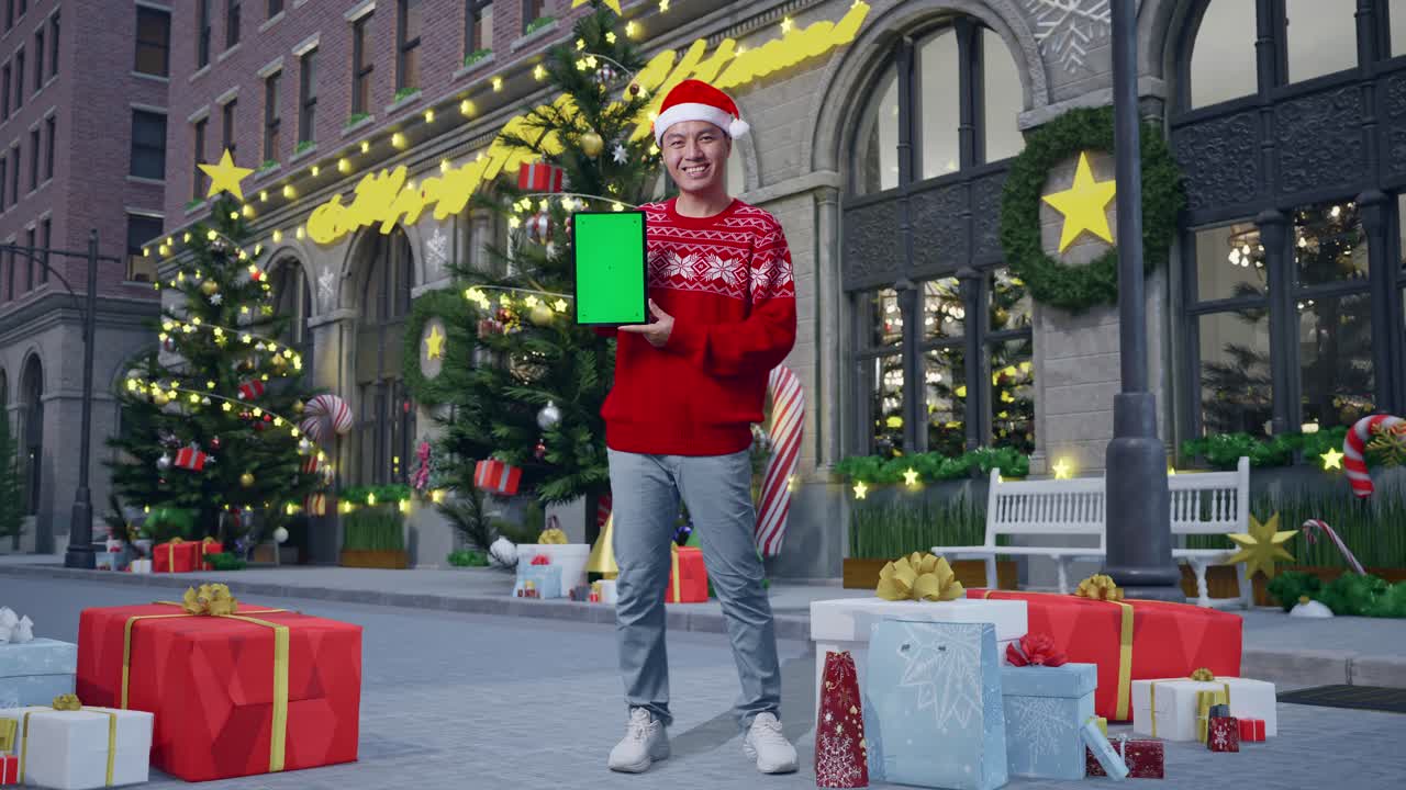 hombre sosteniendo una tableta con pantalla verde frente a las decoraciones de navidad