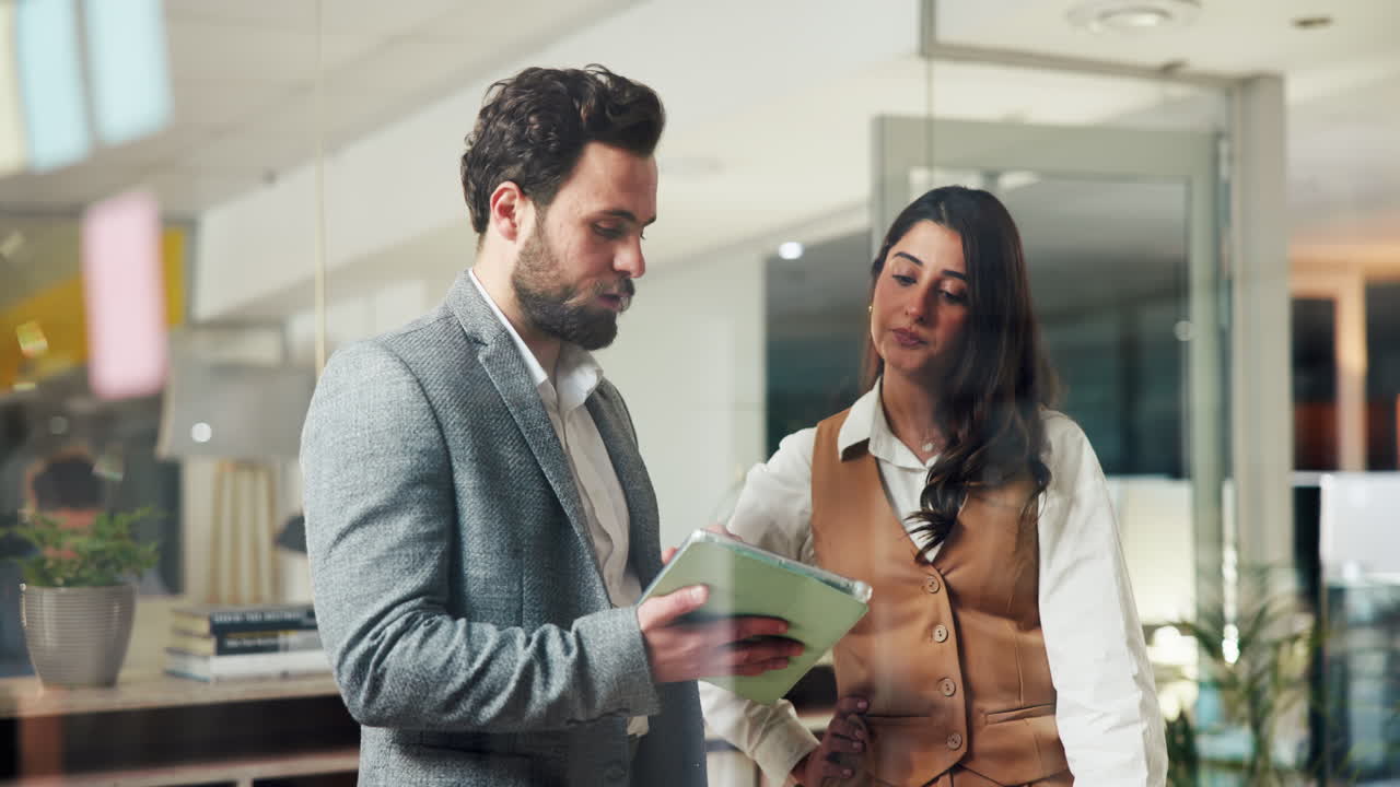 Business professionals discussing work on a tablet in the office