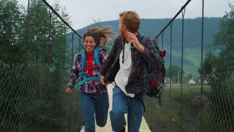 emotional couple travelers running on mountains bridge. hikers race fast outside