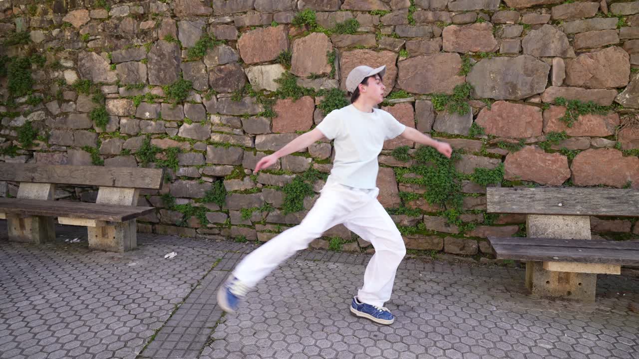 Man Dancing Outdoors by a Stone Wall