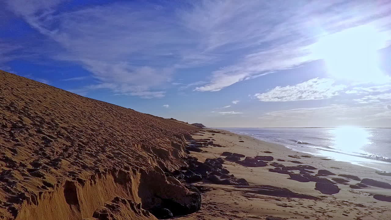 toma aérea de plataforma rodante en nivel bajo y pedestal arriba, duna de pyla a la izquierda y mar a la derecha, cielo azul arriba, francia