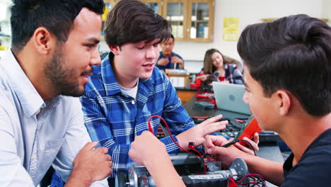 high school teacher with male pupils building robotic vehicle in science lesson