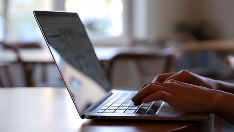 close-up of hands typing on a laptop keyboard