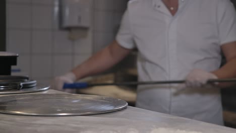 chef caucásico masculino poniendo pizza fresca horneada en la mesa y saliendo. cocinero irreconocible trabajando en la cocina del restaurante en el interior. cocina profesional sabroso plato delicioso. cine 4k prores hq.
