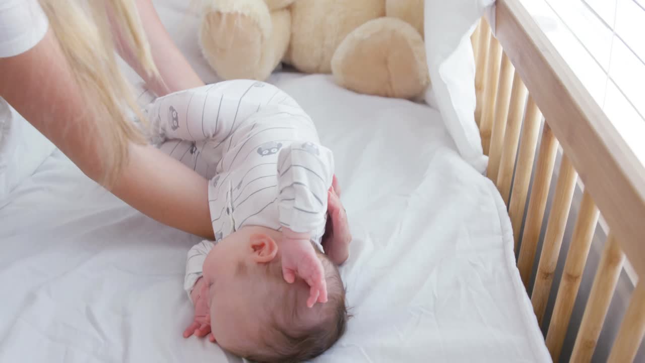 Madre che mette il suo bambino nel lettino