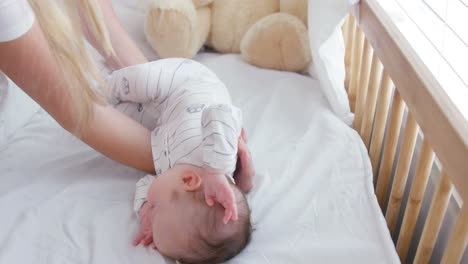 mother putting her baby in his bed