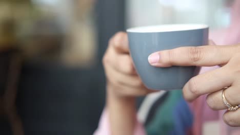 person holding a grey coffee cup