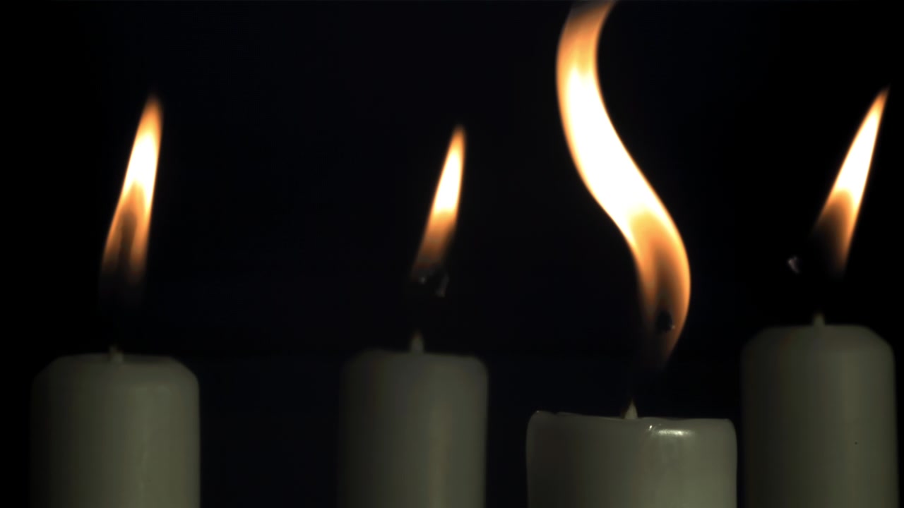 Fiamme di candela che tremolano al rallentatore su sfondo scuro