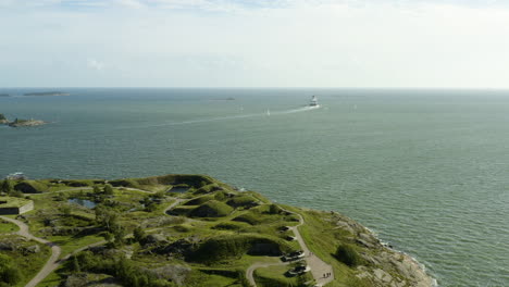 vista aérea de un transbordador de cruceros, alejándose de la isla de suomenlinna, soleado, día de verano, en helsinki, finlandia - seguimiento, disparo de drones