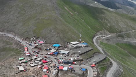 Vista-Aérea-Sobre-Tiendas-Y-Cabañas-En-La-Cima-De-La-Montaña-Y-Camino-Sinuoso-En-El-Paso-De-Babusar