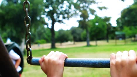 boy hanging on a monkey bar in playground