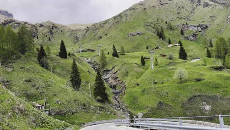 lush green meadows, pine trees, and a mountain stream shape the dramatic curves of giau pass in the dolomites — one of italy’s most scenic alpine routes