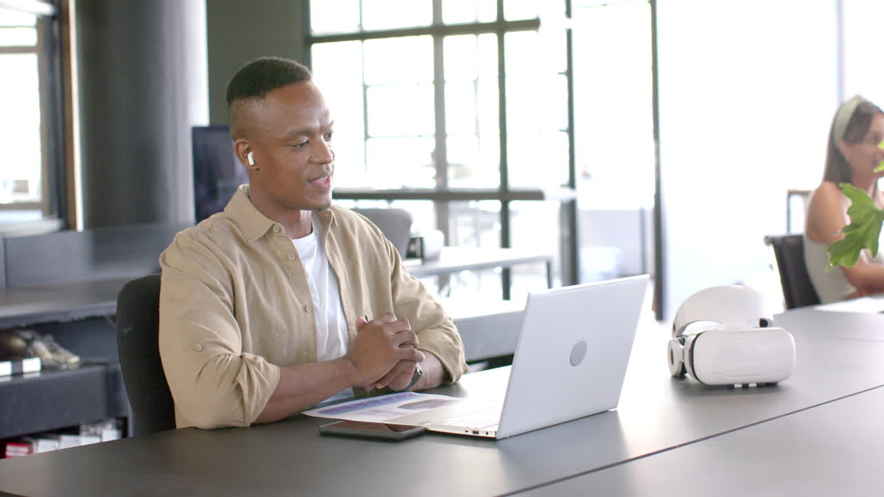 Using laptop and video conferencing, african american man working in modern office environment