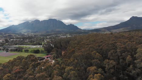 A-shot-rising-over-woods-reveals-a-town-in-front-of-a-mountain