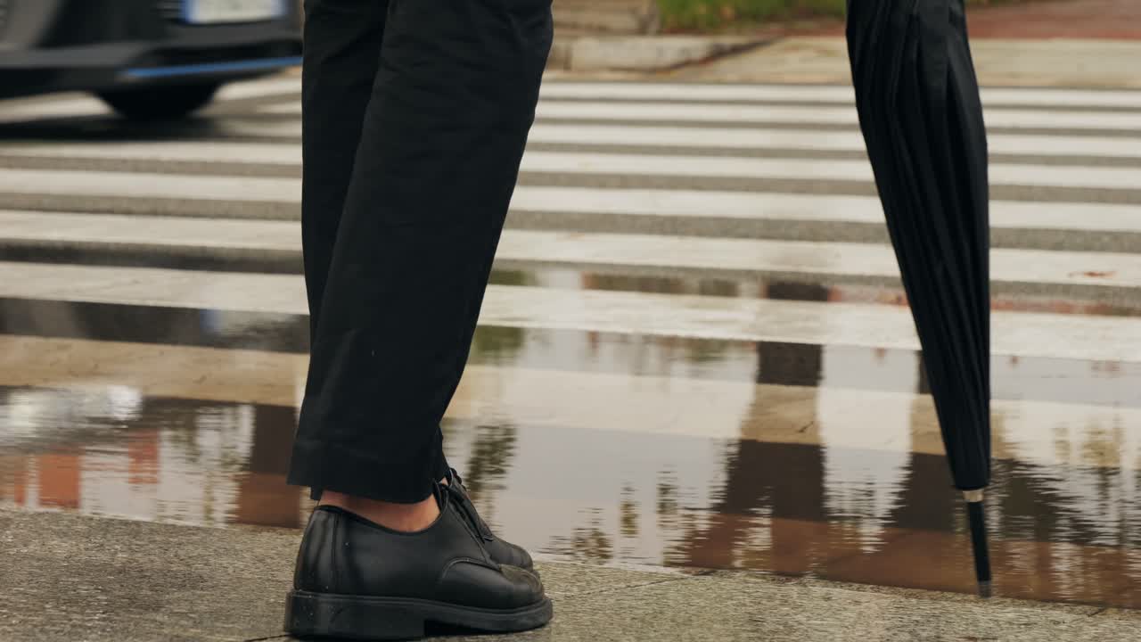 Business man tourist person with umbrella and raincoat on rainy european city street, lights reflecting, walking in Barcelona or Amsterdam during the rain
