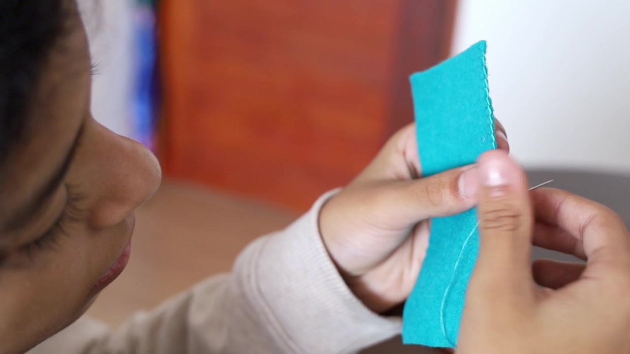 Close-up of hands sewing turquoise felt fabric