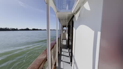 small white boat with a narrow path for visitors travels across a river through nature