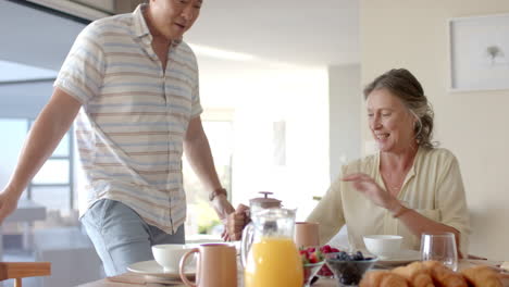 senior couple enjoying breakfast with coffee, orange juice, and croissants