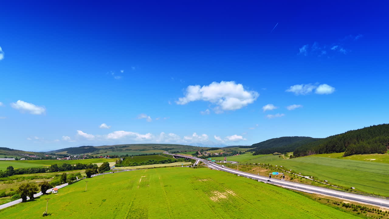 Scenic highway in green hills. A wide-angle view captures a busy highway stretching through lush green fields under a clear blue sky in summer