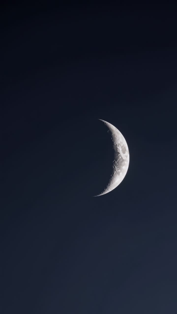 A serene crescent moon captured from a low-angle, set against a dark sky, evoking a tranquil night