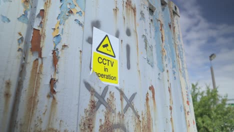 CCTV-in-operation-sign-and-graffiti-in-derelict-urban-area,-slow-motionFleetwood-Docks,-Lancashire,-UK
