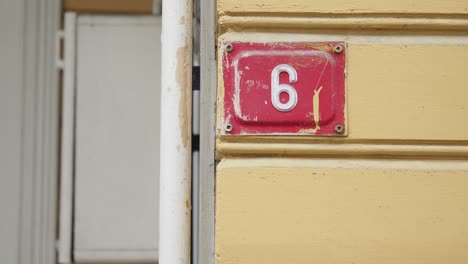 close up of a house number six on a yellow wall