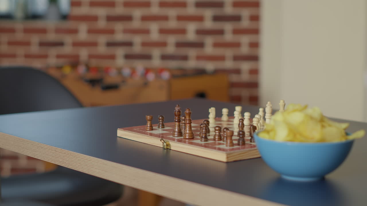 Empty living room table with chess board game and bowl of chips