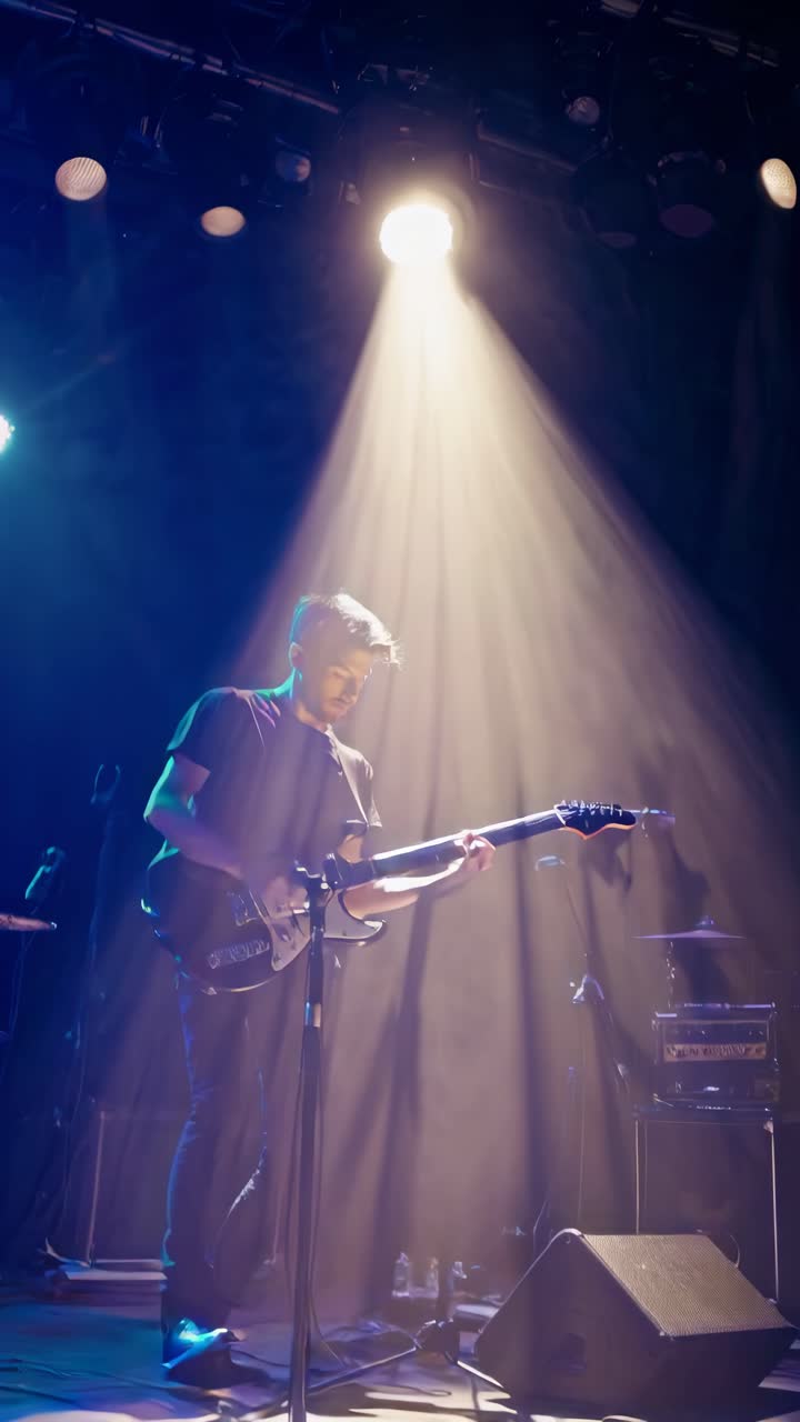 Low-angle video shot of a guitarist on stage, bathed in spotlight