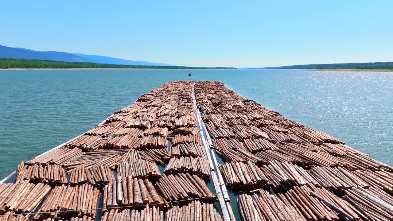 Witness a drone view of a logging tugboat in the remote Canadian wilderness, highlighting climate impact, resource extraction, and the global timber trade.