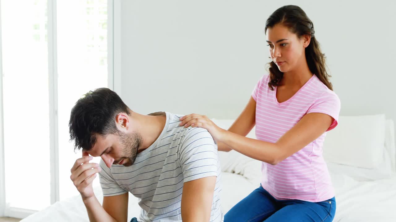 mujer consolando a un hombre sentado en la cama