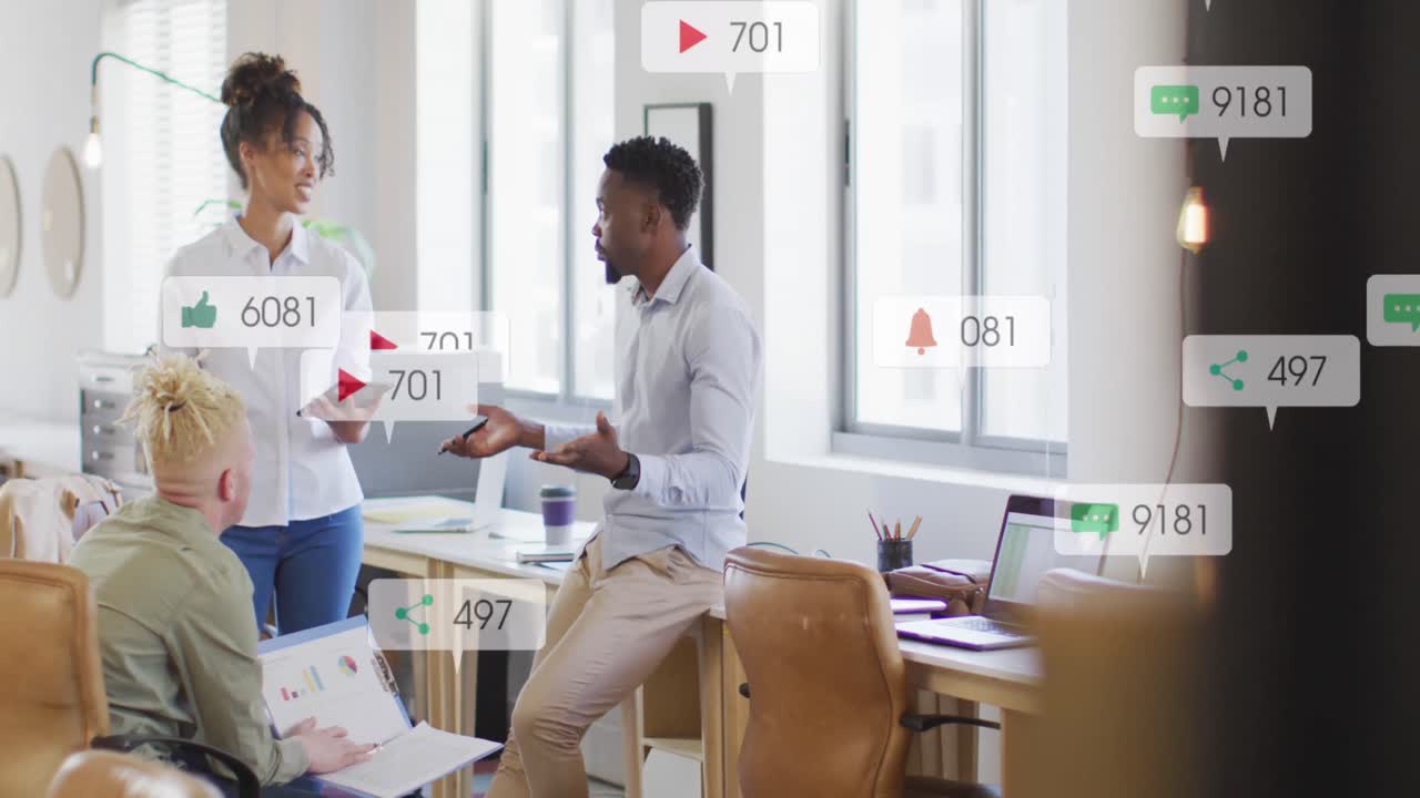Anmation of social media icons falling against diverse colleagues discussing together at office