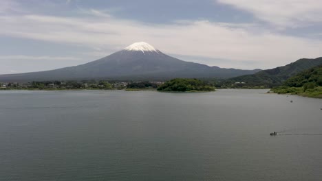 foto aérea del icónico y majestuoso volcán monte fuji con un paisaje pintoresco, el lago kawaguchi, un barco y un pico cubierto de nieve en fuji, japón