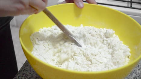 closeup mixing flour and yeast, with wooden spoon