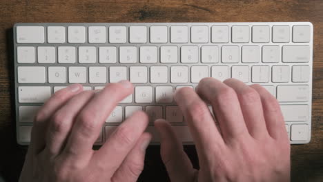 top down close up of male hands typing on bluetooth keyboard