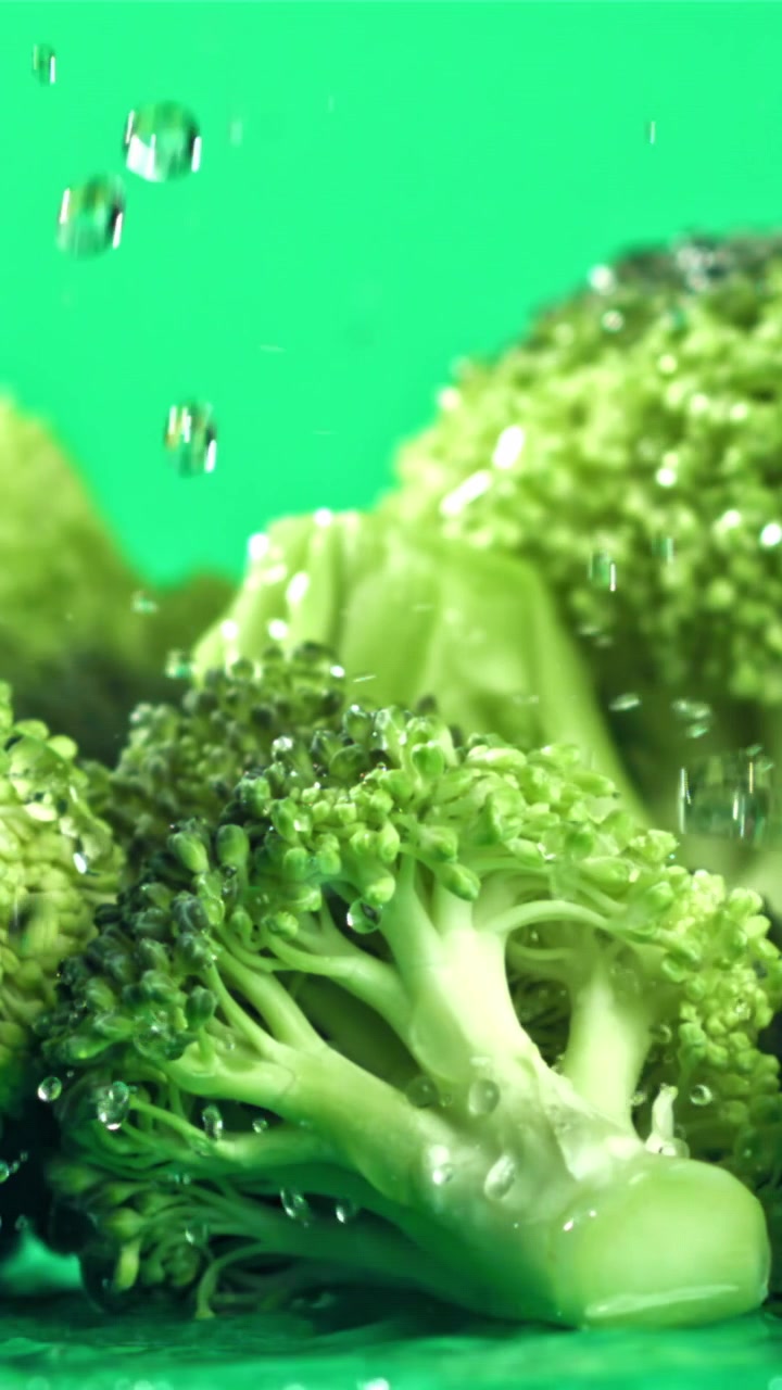 Acqua che schizza su cimette di broccoli freschi e verdi.