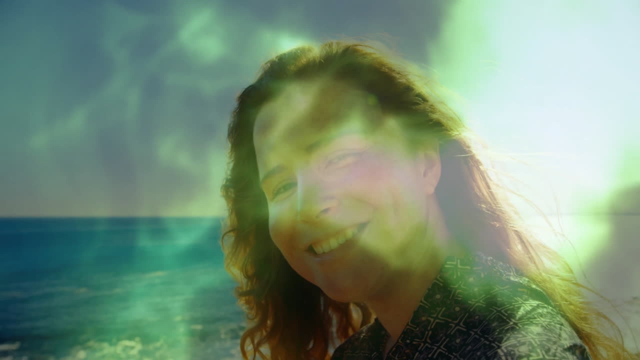 At beach, person smiling with green light animation overlaying scene