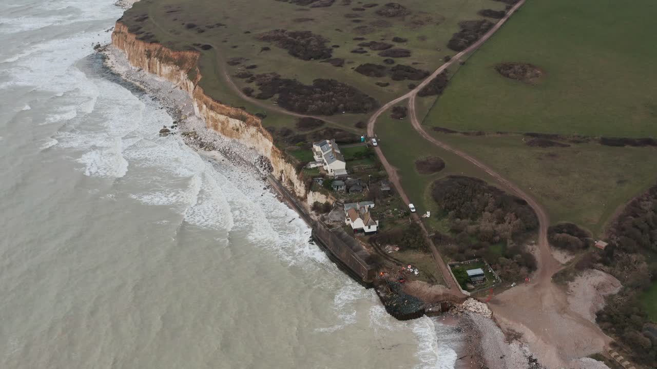 Ripresa con drone in rotazione di piccoli cottage su bianche scogliere di gesso nell'Inghilterra meridionale