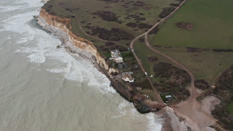 toma de drones giratorios de pequeñas cabañas en acantilados de tiza blanca en el sur de inglaterra.