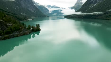 turquoise lake waters flowing past under drone flying at loen, western norway