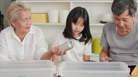 little girl and her family helping to separate plastic bottle into recyclable bin at home together.