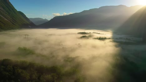 morning mist over the valley among the mountains in the sunlight. fog and beautiful nature of norway aerial footage.