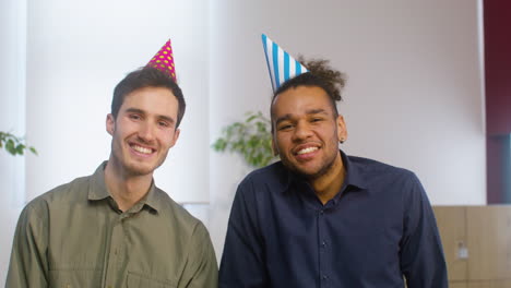 Portrait-Of-And-American-Men-With-Party-Hat-Smiling-And-Looking-At-The-Camera-At-The-Office