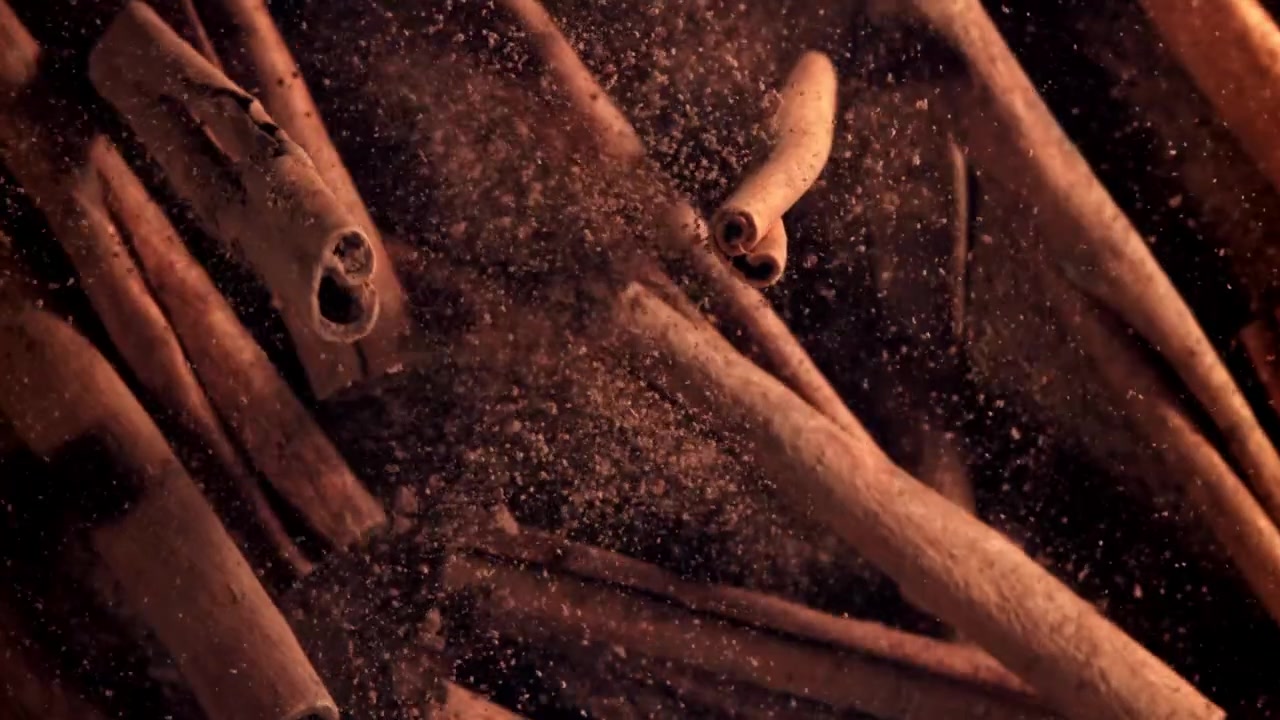 Kanelstenger og kanelpulver faller i sakte film