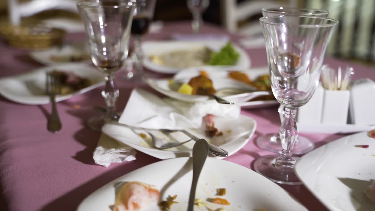 holiday table after the fun. Leftovers of food in the plates and dirty napkins are on the table. Camera motion forward