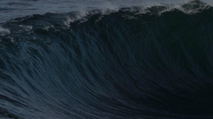 Surfer pulls back on board as powerful wave glistens as it breaks