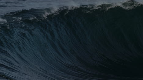 surfer pulls back on board as powerful wave glistens as it breaks