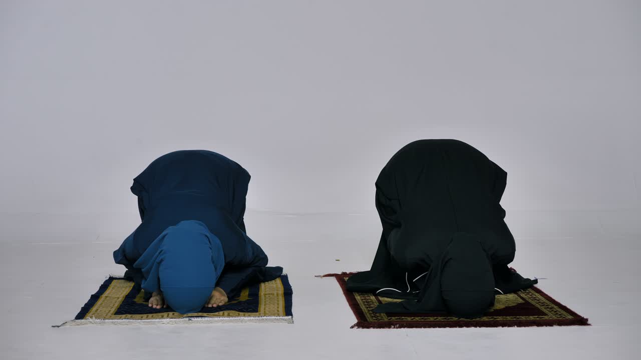 전통적인 히자브를 입은 두 명의 아시아 무슬림 젊은 여성들이 모스크에서 하나님을 찬양하고 이슬람 신앙을 실천하고 있습니다.