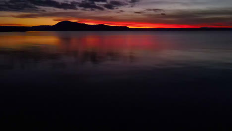 Crepúsculo-Amanecer-Sobre-Colinas-Tomadas-Desde-El-Borde-De-Un-Gran-Lago---Deslizamiento-De-Drones-A-Ramas-De-árboles---Océano-Y-Mar-Almacen-De-Videos