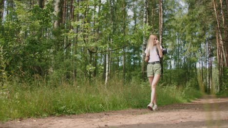 adult woman wearing shorts and t-shirt hikes through woods. young lady hiking