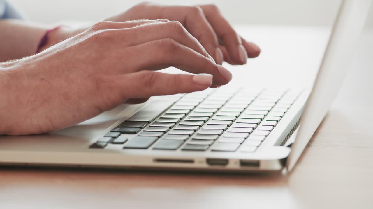 Close-up view of hands typing on a laptop keyboard.